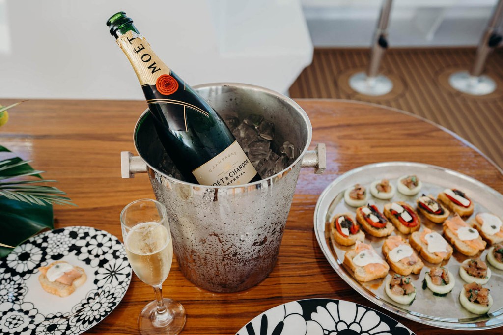 Champagne in ice bucket with appetizers on a wooden table.