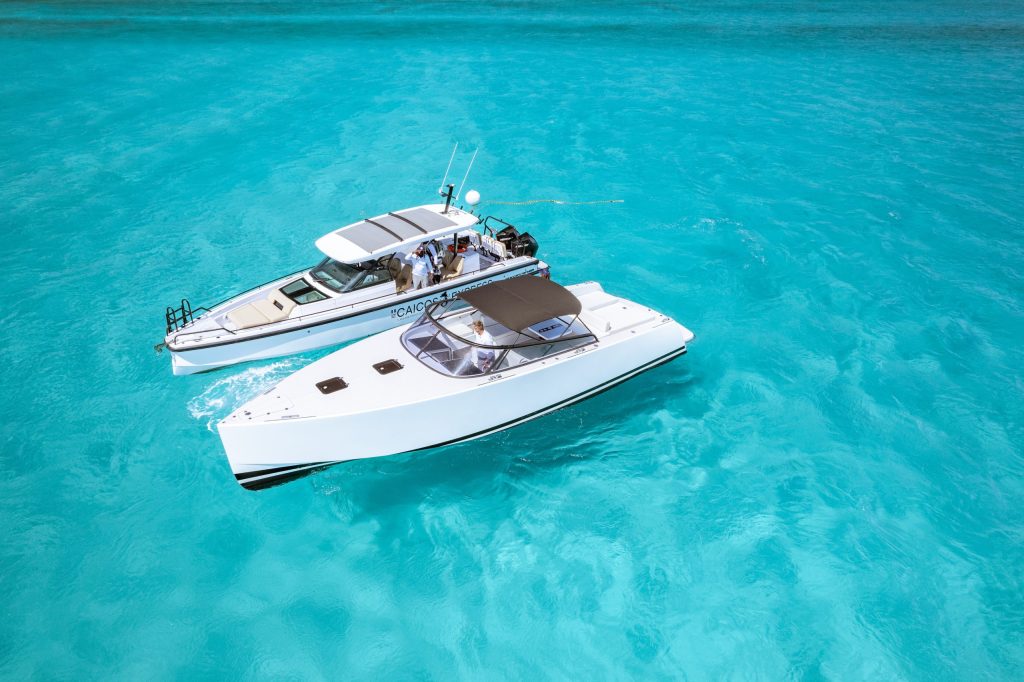 Two white boats floating on clear turquoise water viewed from above.