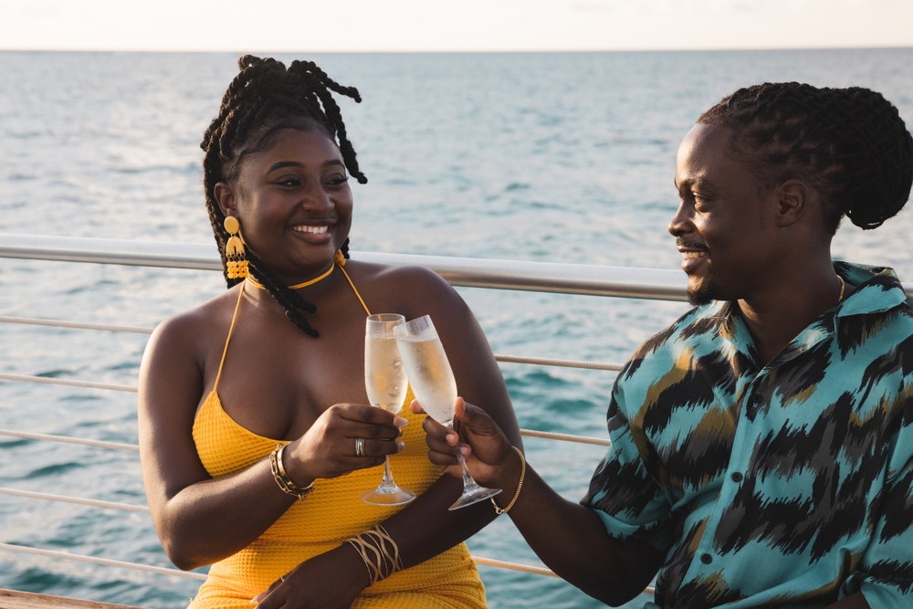 Couple on a sailboat toasting with iced champagne glasses.