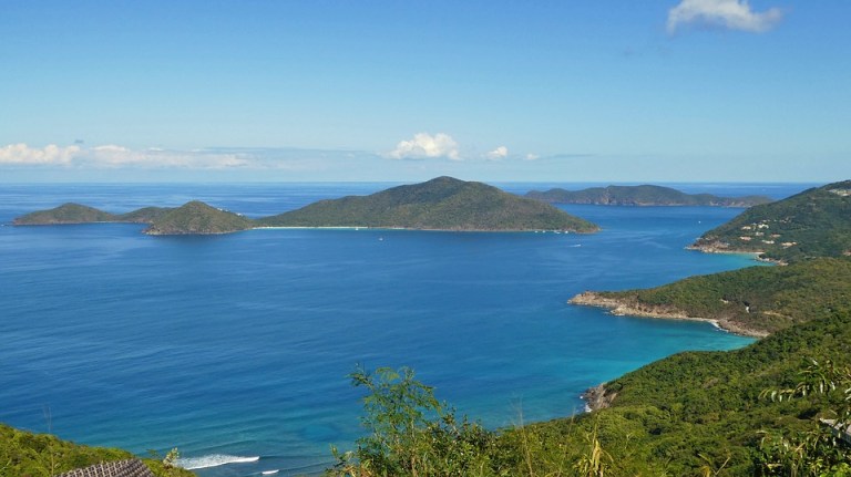 Scenic view of ocean and islands with clear blue sky and green hills in the foreground.