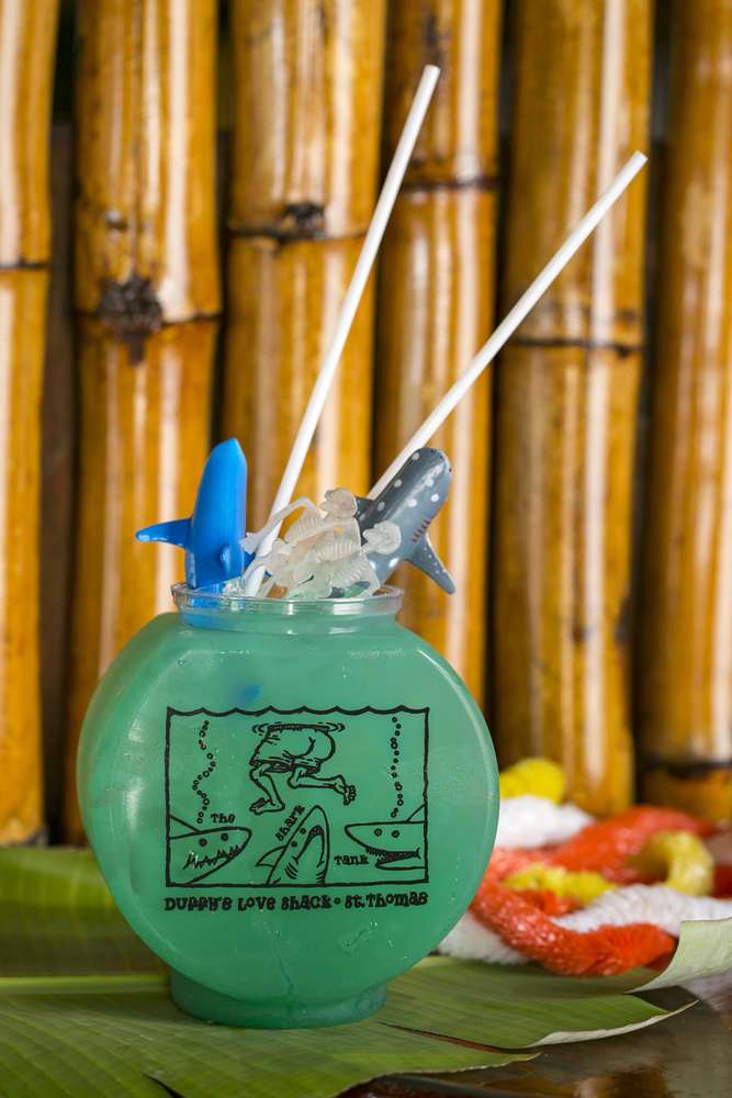 A blue cocktail in a round glass with straws on a bamboo background.